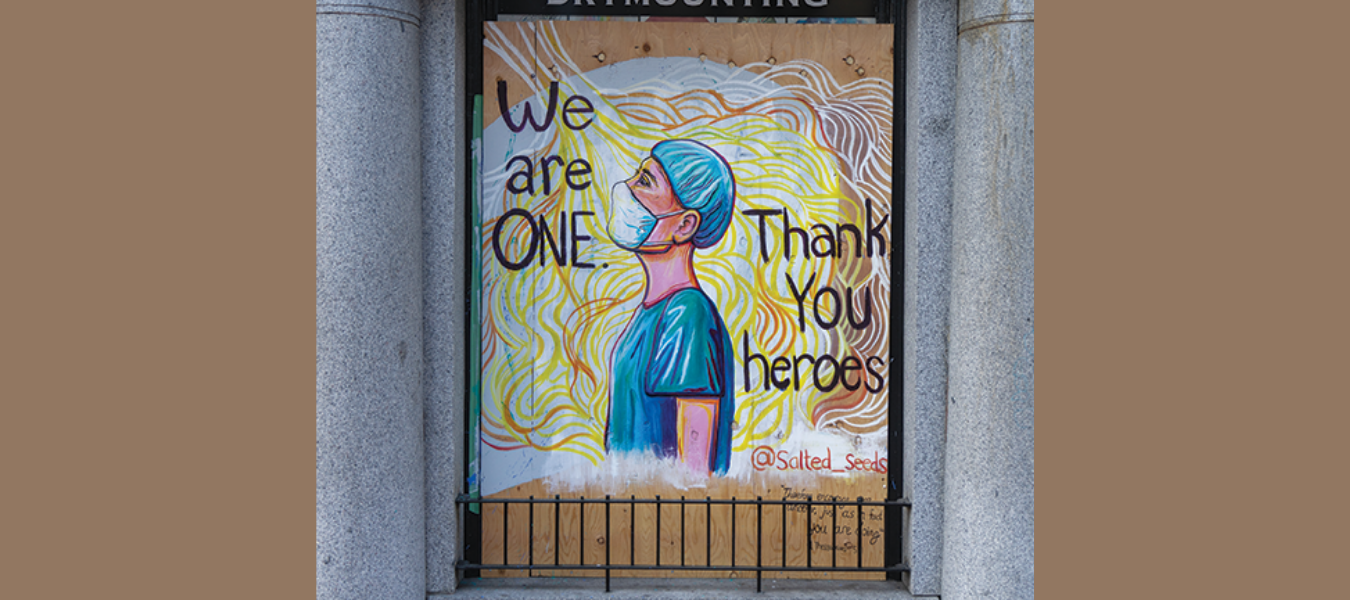 Mural of a person in scrubs and facemask, with the text "We are One, Thank you Heroes" written around it
